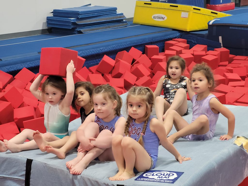 Girls team seated preparing to practice gymnastics
