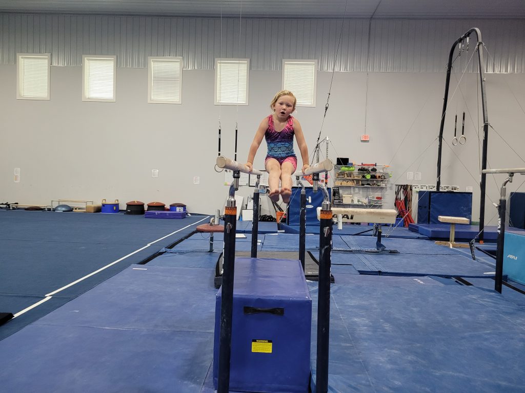 A child practicing on parallel bars at Kids Night Out
