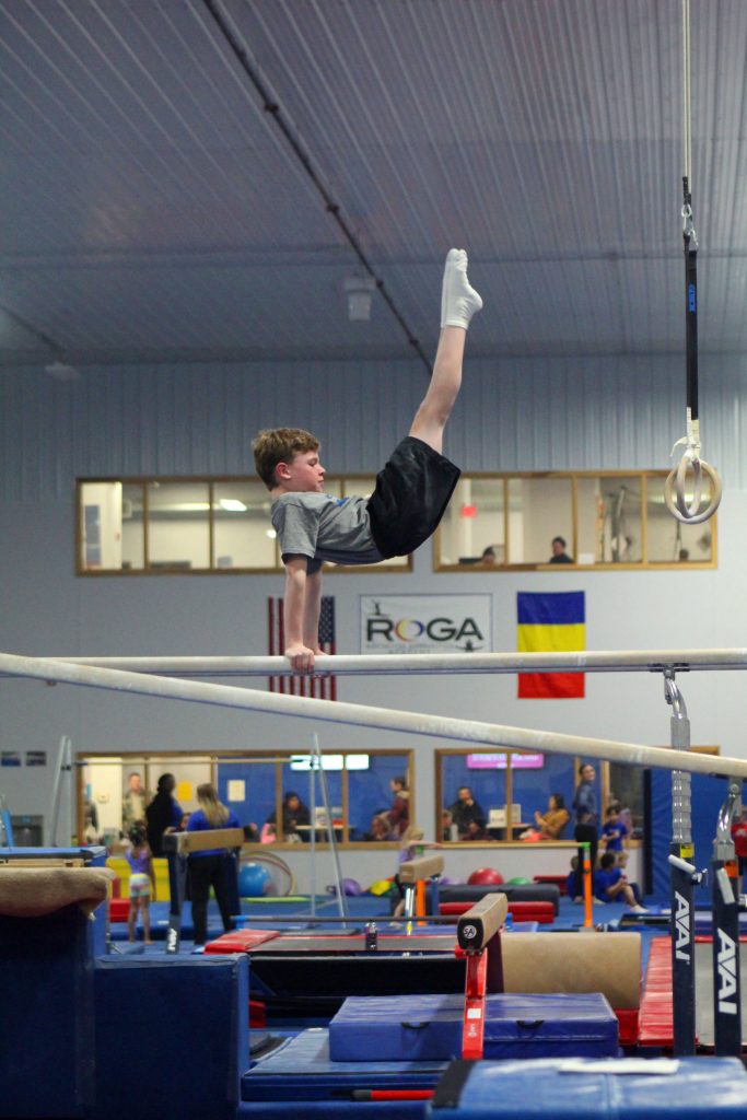A boy demonstrating a gymnastics movement on parallel bars