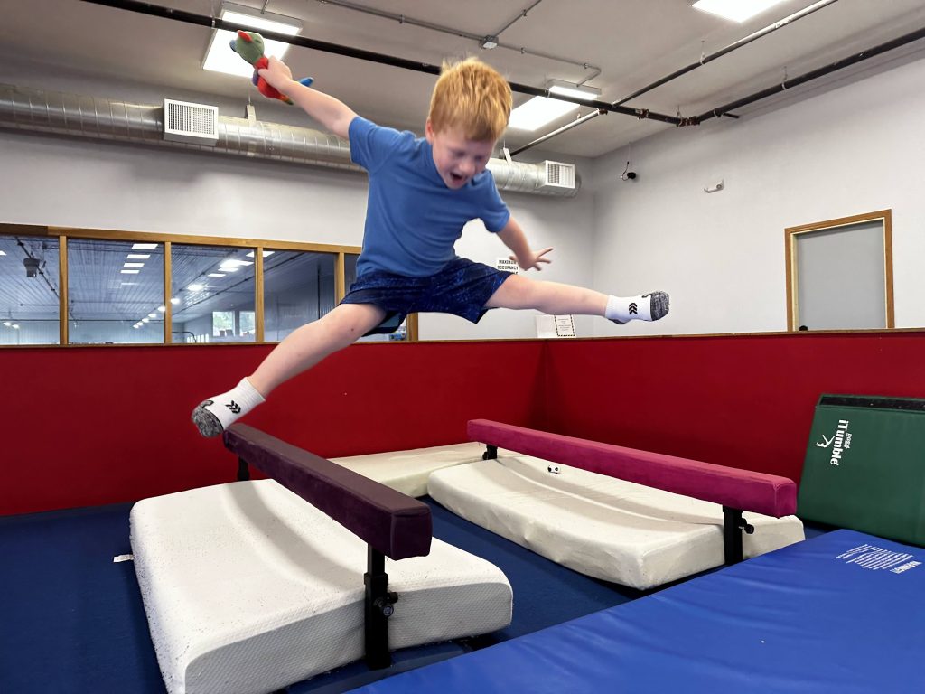 A boy jumping near a balance beam