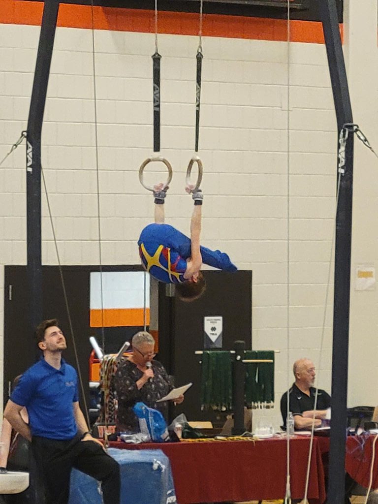 A boy doing a movement on rings