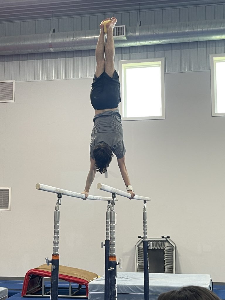 A boy demonstrating a handstand on the parallel bars