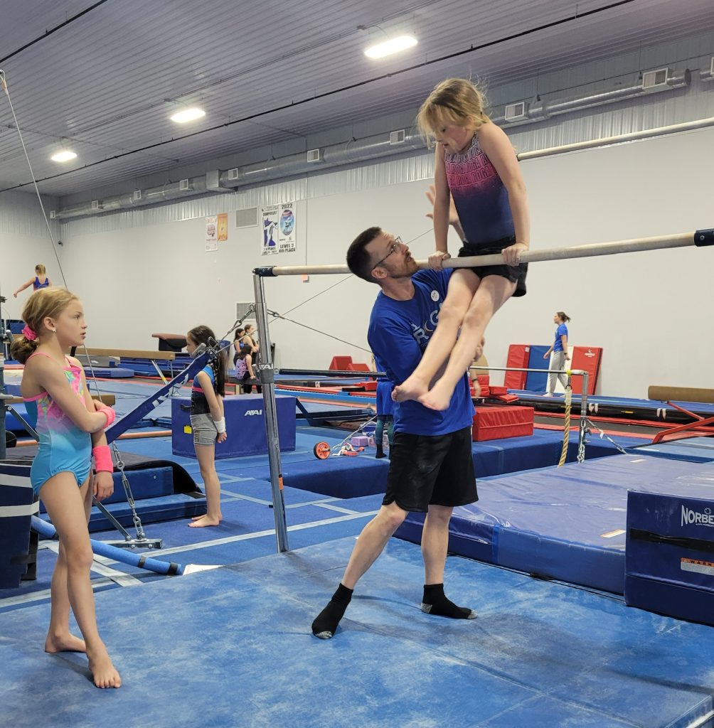 A girl receiving instruction on a gymnastics movement