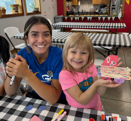 A coach and camper pose for a picture with craft