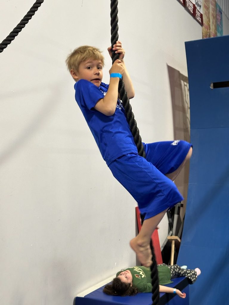 A boy climbing a rope at a summer camp
