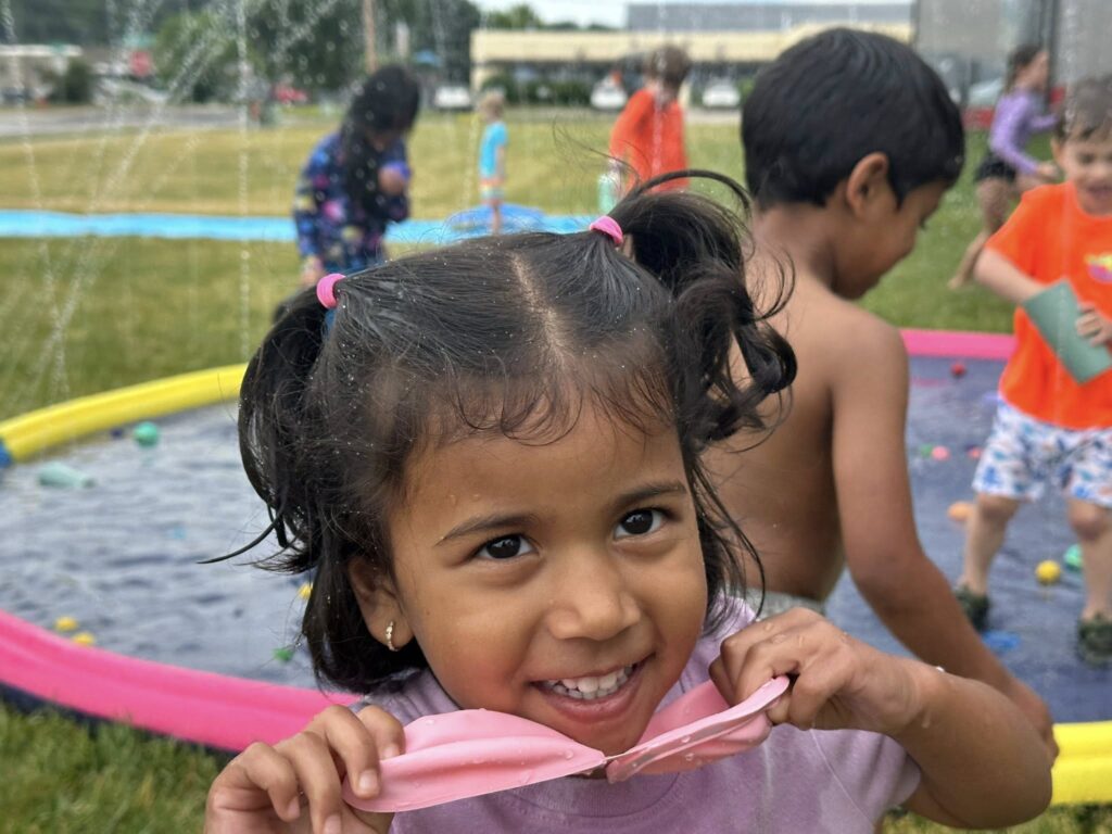 Smiling camper enjoying water day during Camp ROGA's space-themed gymnastics summer camp.