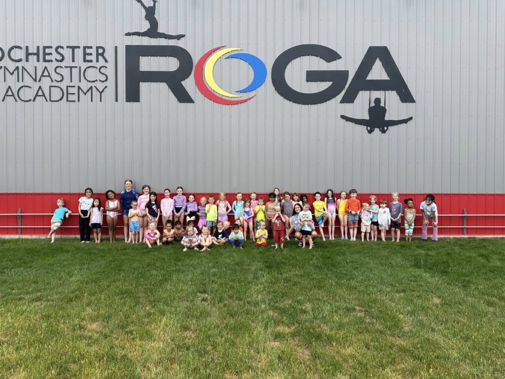 Camp ROGA gymnasts and counselors gathered outside Rochester Gymnastics Academy for a group photo during summer camp.