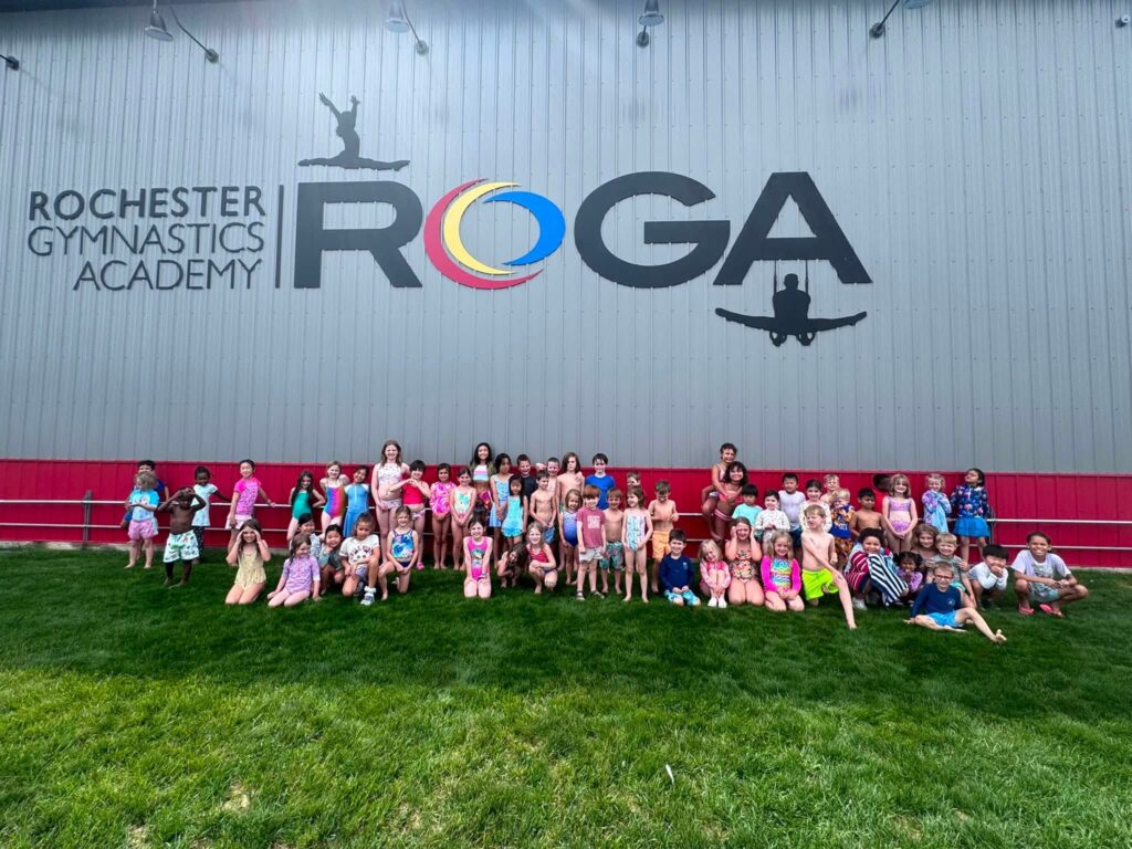 Camp ROGA campers gather outside Rochester Gymnastics Academy for a group photo celebrating Olympic-themed summer camp week.