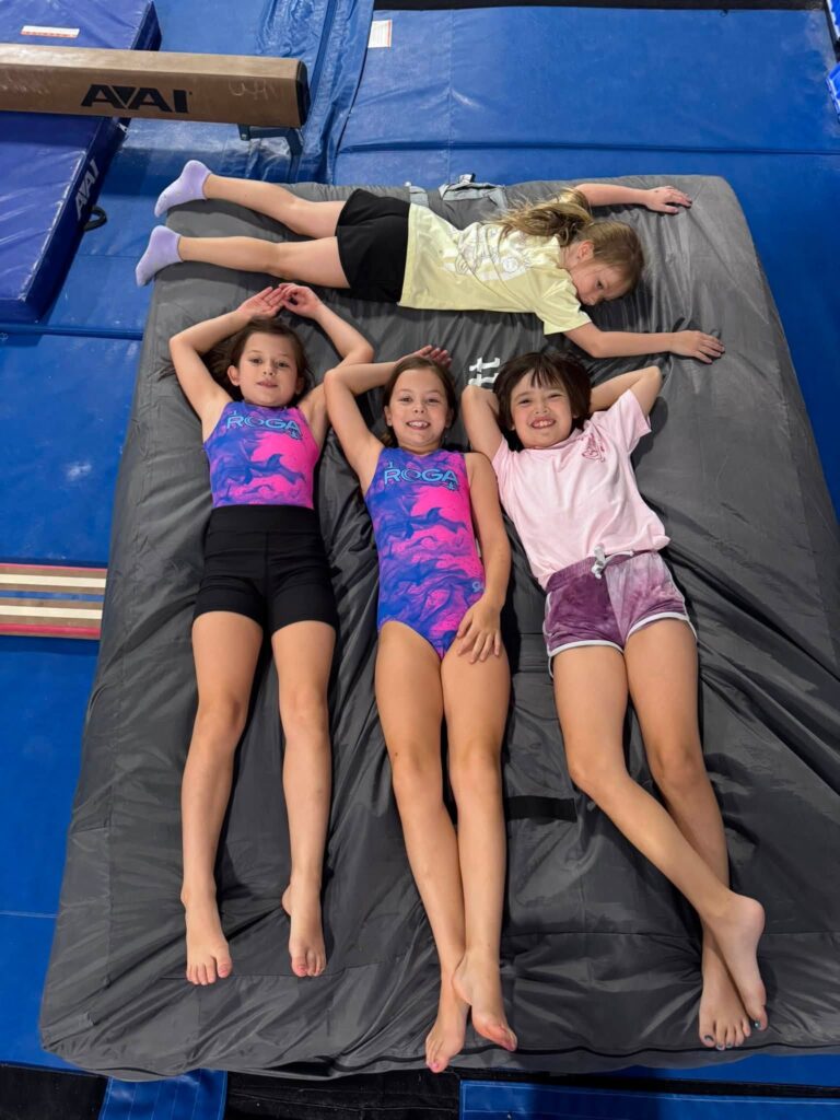 Camp ROGA campers relax together on a gymnastics mat during Pirate Treasure Quest week at Rochester Gymnastics Academy.